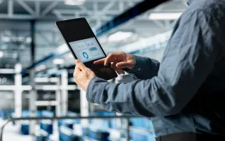 ProfessionaEin Mitarbeiter betrachtet ein Daten-Dashboard auf einem Tablet in einer modernen Fabrik. technologist checking production