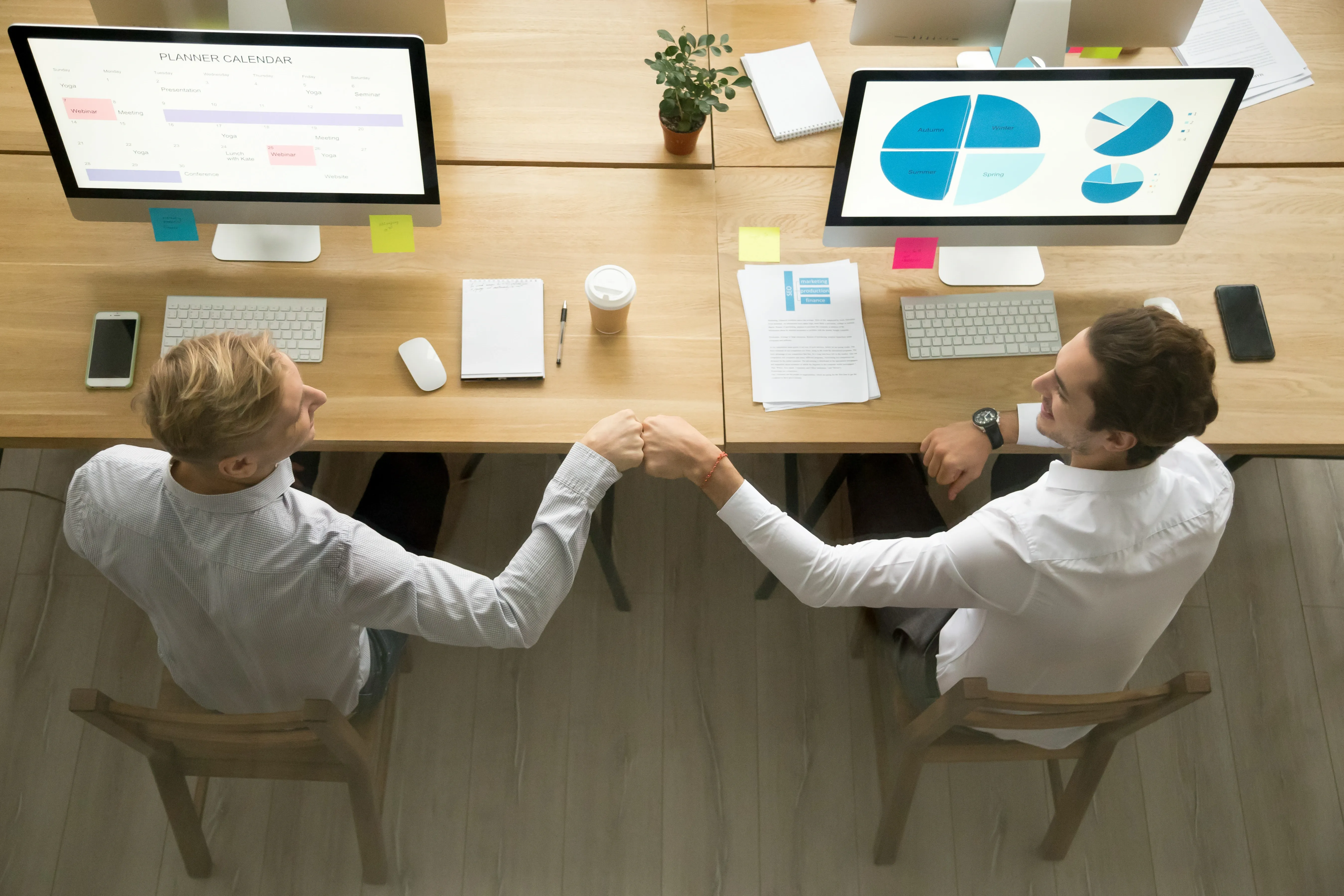 Colleagues bumping their fists in front of their desk