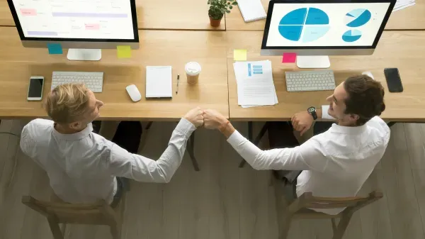 Colleagues bumping their fists in front of their desk